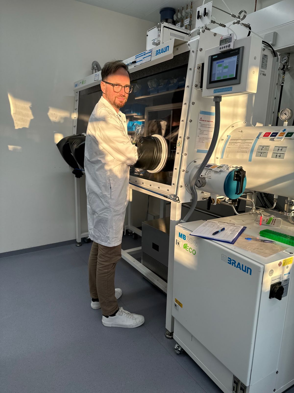 A man wears a laboratory coat. His hands are inside a safety laboratory hood. A man wears a laboratory coat. His hands are inside a safety laboratory hood.