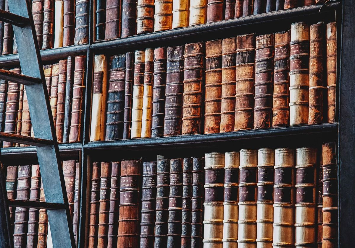 A bookshelf in a library filled with old books. A bookshelf in a library filled with old books.