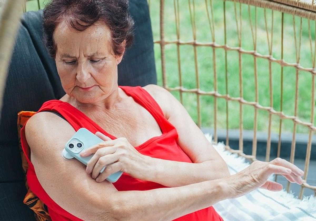 A woman with diabetes checks her blood glucose levels using a wearable biosensor patch on her upper arm, transmitting the results to a smartphone. A woman with diabetes checks her blood glucose levels using a wearable biosensor patch on her upper arm, transmitting the results to a smartphone.