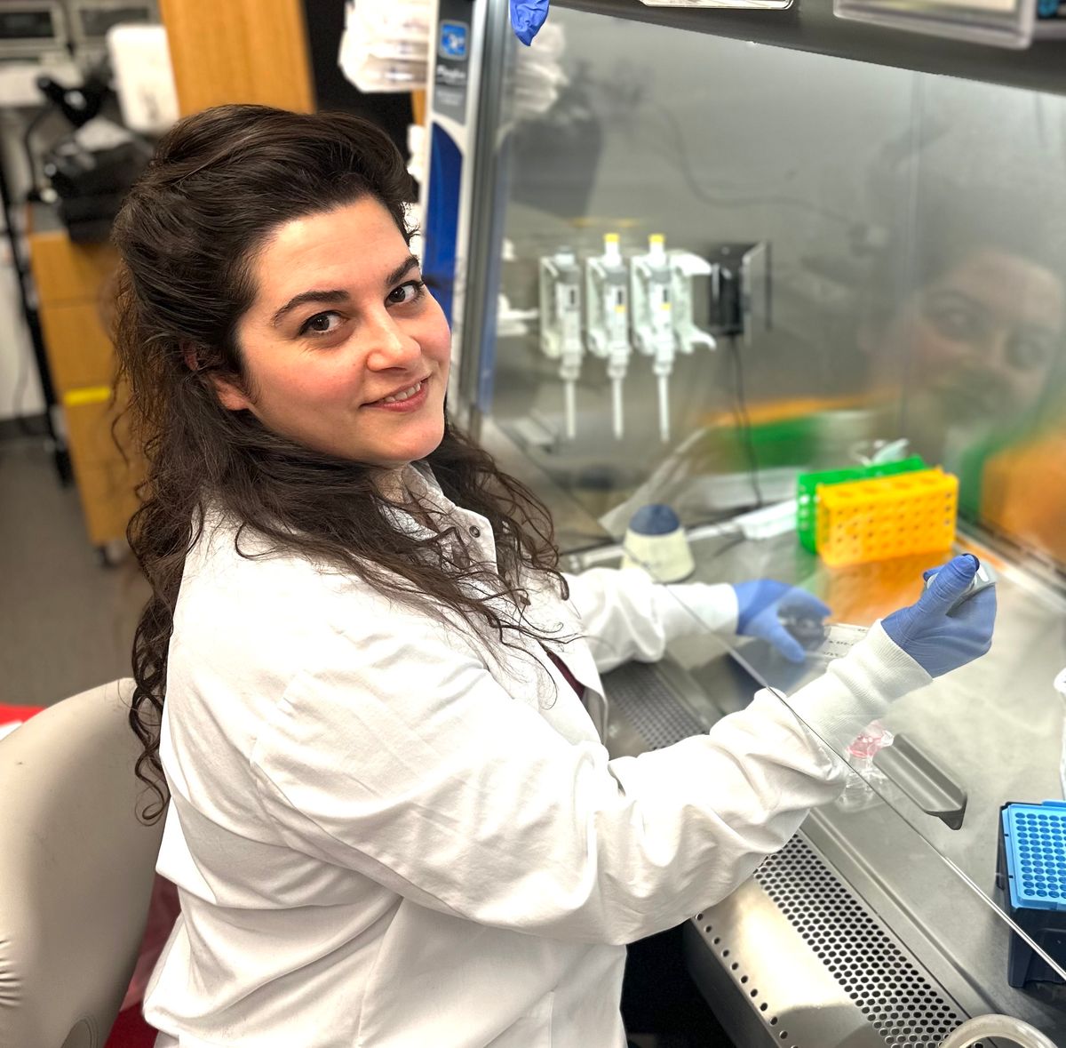 Image of Gizem Gumuskaya working under a laboratory fume hood. Image of Gizem Gumuskaya working under a laboratory fume hood.