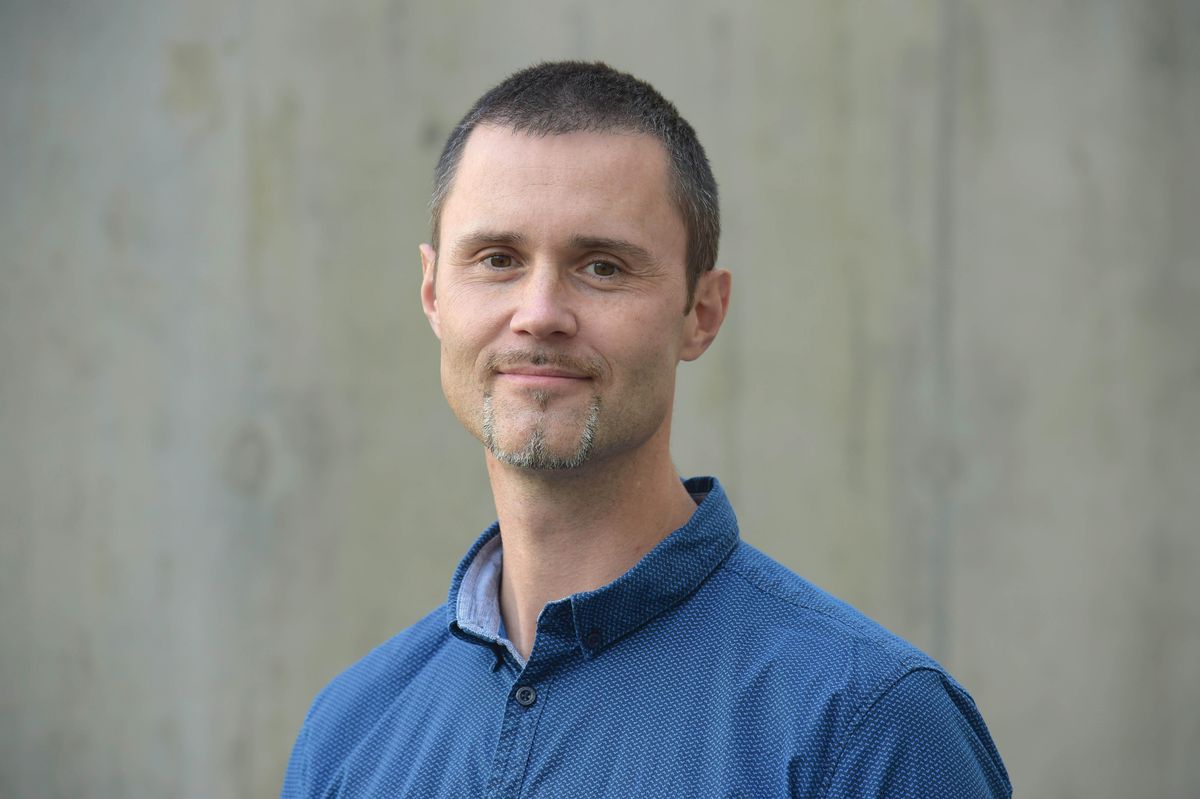 Michael Hiller wears a blue shirt and stands outside against a grey wall. Michael Hiller wears a blue shirt and stands outside against a grey wall.