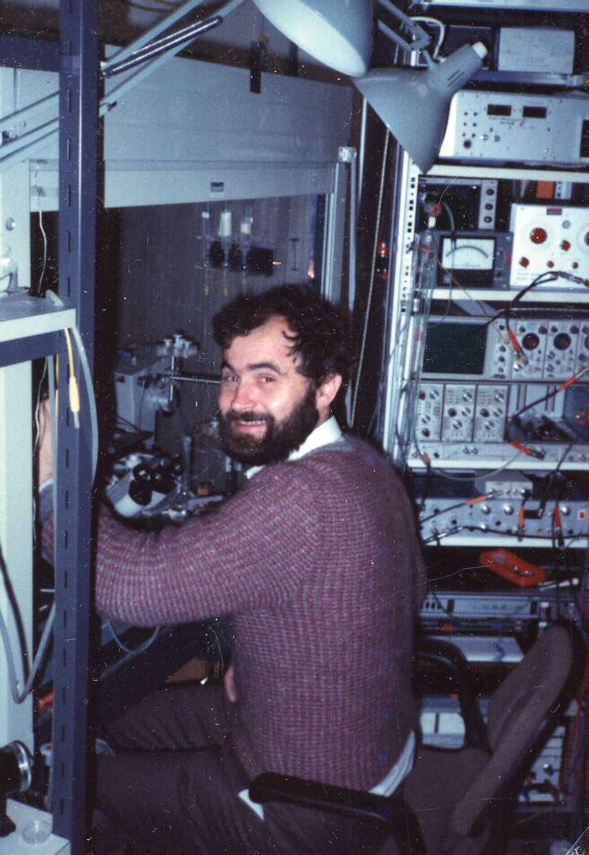 A man smiles back at the camera as he sits in front of a fume hood. A man smiles back at the camera as he sits in front of a fume hood.
